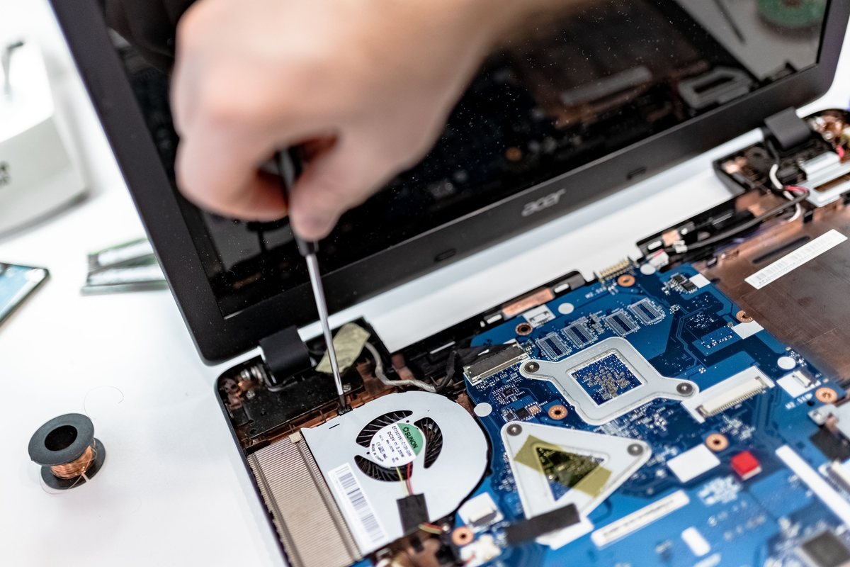 Technician repairing the internal hardware of a laptop
