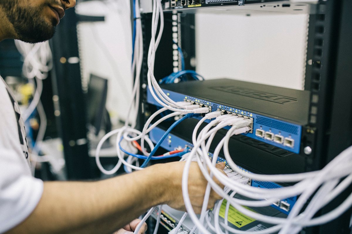 Network engineer configuring Ethernet cabling and network equipment